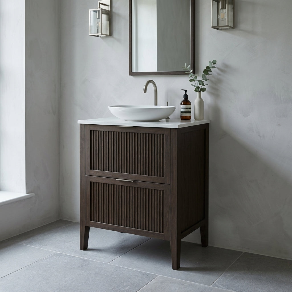 Mockridge Design Clifton 600mm floor-standing single vanity in dark roast stained oak with deep espresso grain figuring and vertical fluted drawer fronts set within shaker frame borders, Calacatta quartz worktop, oval ceramic sit-on basin and brushed nickel deck-mounted vessel mixer tap, styled in a refined moody English bathroom with pale dove grey lime-washed plaster walls and honed Belgian bluestone floor