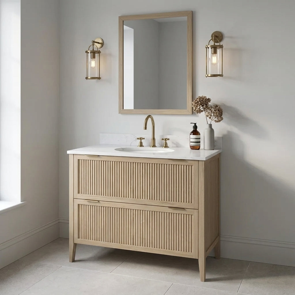 Mockridge Design Clifton 1000mm floor-standing single undermount vanity in Smoke 5% stained oak with soft dusty ash-blonde grain figuring and vertical fluted drawer fronts set within shaker frame borders, Calacatta quartz worktop, undermount ceramic basin and brushed brass deck-mounted vessel mixer tap, styled in a contemplative English bathroom with pale dove grey walls and honed English limestone floor
