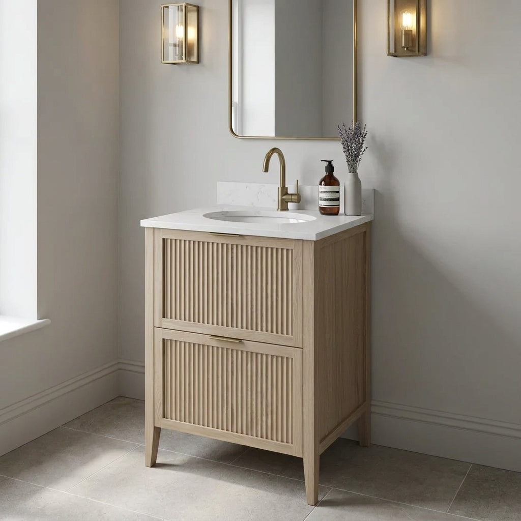 Mockridge Design Clifton 600mm floor-standing single undermount vanity in Smoke 5% stained oak with soft dusty ash-blonde grain figuring and vertical fluted drawer fronts set within shaker frame borders, Calacatta quartz worktop, undermount ceramic basin and brushed brass deck-mounted vessel mixer tap, styled in a contemplative English bathroom with pale dove grey walls and honed English limestone floor